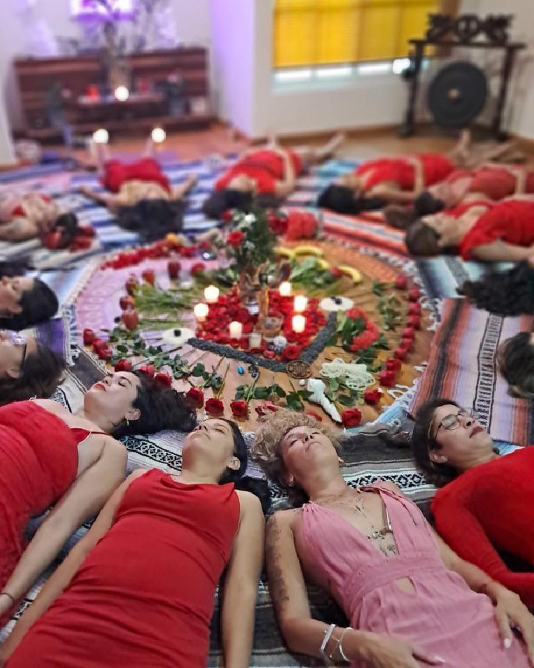 Un círculo de participantes descansando alrededor de un mandala de rosas y velas